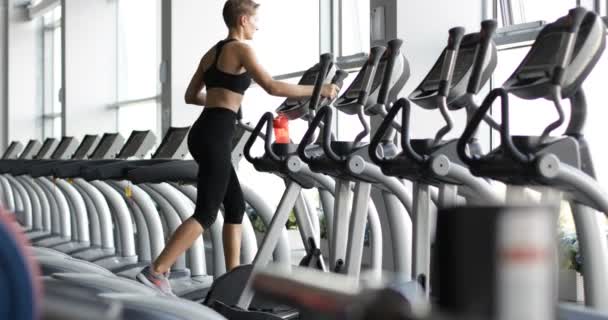 Vista de la bonita mujer deportiva corriendo en la cinta de correr . — Vídeo de stock