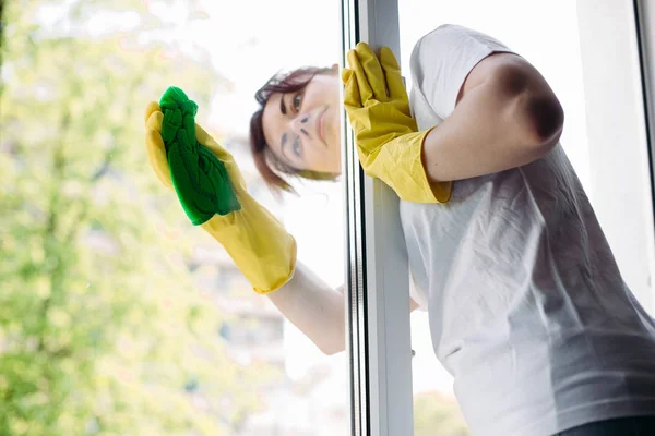 Morena ama de casa limpieza ventana sucia grande. Concepto de tareas domésticas y servicio de apartamentos . — Foto de Stock