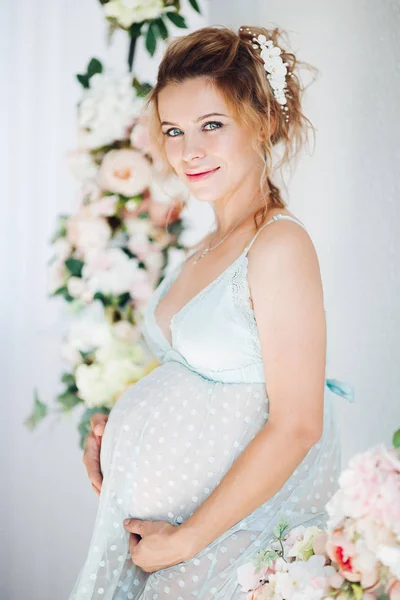 Senzualitate gravidă în rochie de lenjerie îmbrățișând stomacul și zâmbind . — Fotografie, imagine de stoc
