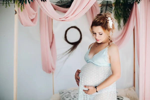 Blonda gravida femeie culcat pe pat atingere de mâini pe stomac . — Fotografie, imagine de stoc