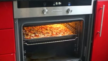 Kadın fırın mutfak at açılış ve pizza veya güveç ızgara kapat.