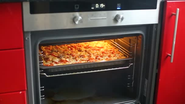 여성 부엌에 오븐 열고 피자 또는 캐 서 롤을 굽고의 클로즈업. — 비디오