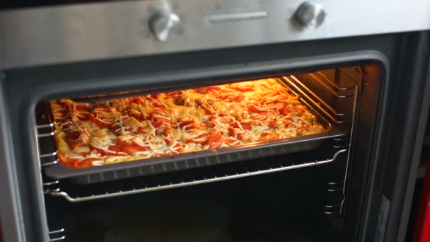 Menutup oven pembukaan perempuan di dapur dan memanggang pizza atau casserole . — Stok Video