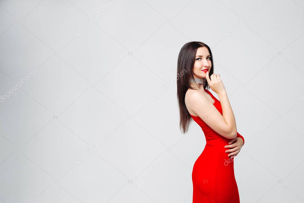 Seductive brunette in bright red dress and chocker with hand at 