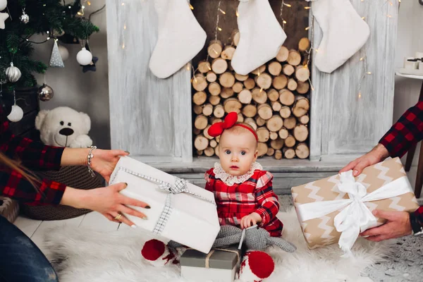 빨간 드레스와 머리 띠 벽난로에서 부모 로부터 선물을 받는 사랑 스러운 아기. — 스톡 사진