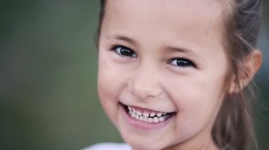 Oldukça küçük esmer kız ve mutlu kameraya gülümseyen.