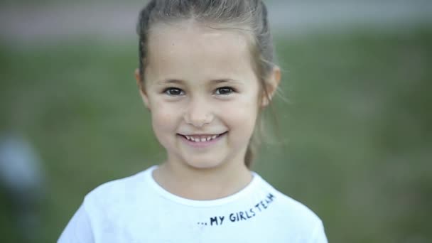 Ganska liten brunett tjej tittar och lycklig ler mot kameran. — Stockvideo
