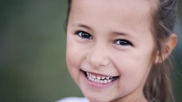 Довольно маленькая брюнетка девушка смотрит и счастливо улыбается в камеру . — стоковое видео
