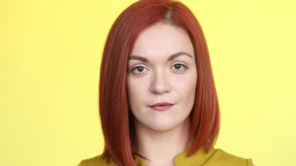Femme aux cheveux rouges positifs souriant à la caméra, posant sur fond jaune . — Video
