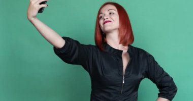 Mavi gözleri ve kıvırcık saçlı, Yeşil elbiseli güzel esmer görünüyor içine kamera ve yavaşça ağzına sağ eliyle kapsayan. Gri bir arka plan üzerinde izole