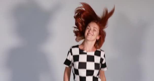 Schöne glückliche rothaarige Mädchen im Musterkleid tanzen und springen im Studio. — Stockvideo