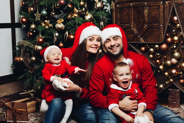 Happy family with two adorable kids having fun at Christmas tree.