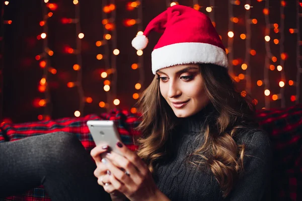 스마트 휴대 전화를 사용 하 여 빨간 산타 모자에 화려한 여자. — 스톡 사진
