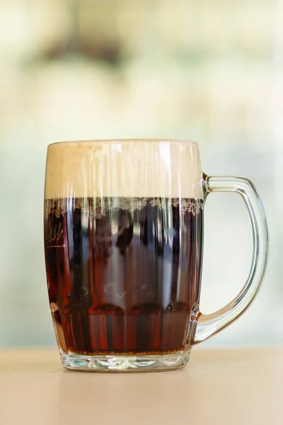 Photo of glass beer cup standing on smooth wooden surface.