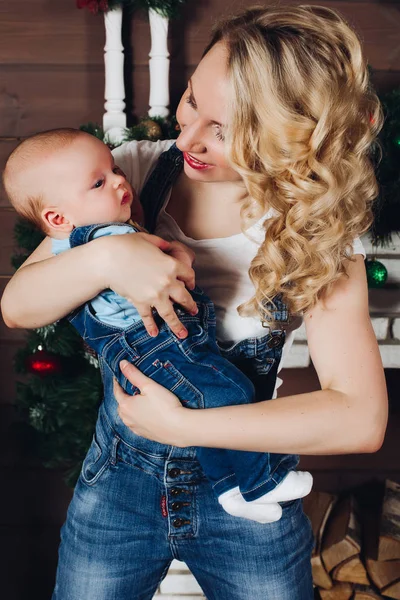 Niño con hermosa mamá rubia abrazando en estudio decorado para Navidad . — Foto de Stock