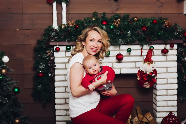 Niño con hermosa mamá rubia abrazando en estudio decorado para Navidad . —  Fotos de Stock