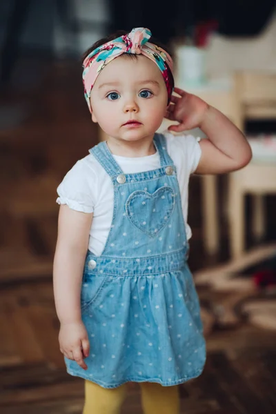 Pequena menina bonito e bonito em vestido de jeans e bandagem na cabeça em estilo retro . — Fotografia de Stock
