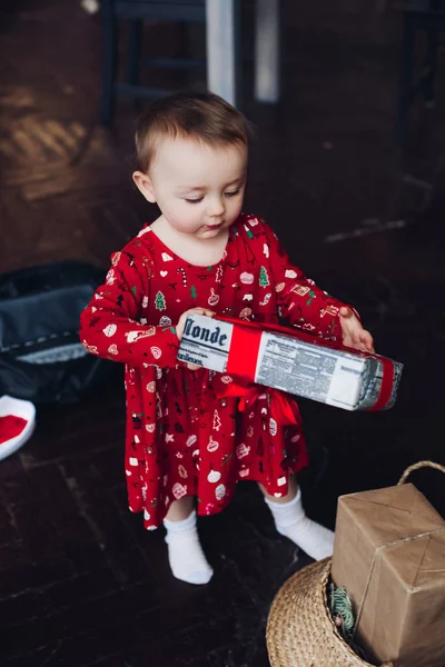 Gelukkig vrij klein meisje in de rode pajama dress openen Kerstcadeaus. — Stockfoto