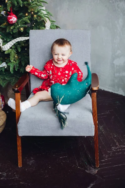 Adorable niño en vestido rojo con estampado de Navidad sentado en silla . —  Fotos de Stock