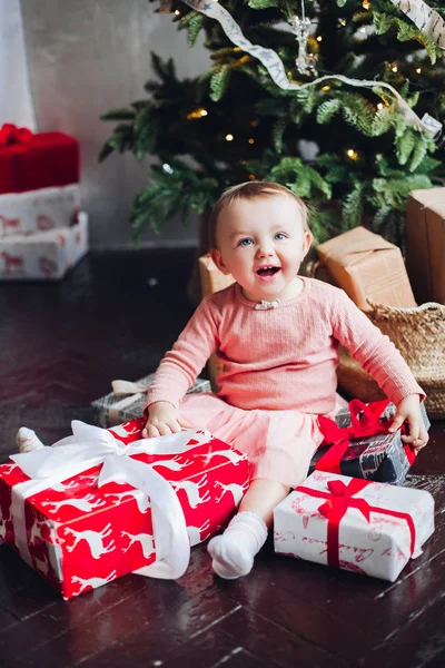 Retrato de niña feliz sentada en el techo en un estudio decorado y jugando con regalos de Navidad . — Foto de Stock