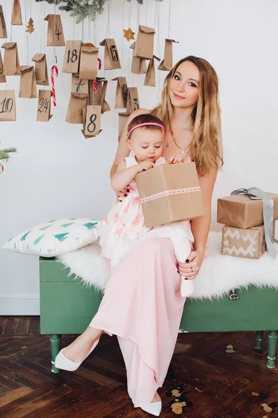 크리스마스 장식 근처 재생 핑크 드레스에 작은 딸과 함께 아름 다운 엄마. — 스톡 사진