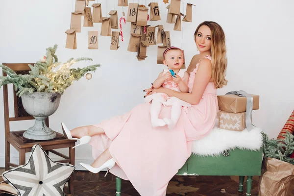 Pembe elbiseler Noel dekorasyonu oynayan küçük kızı ile güzel anne.