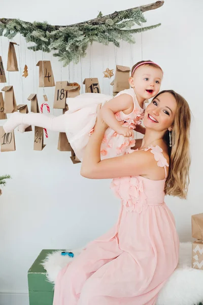 크리스마스 장식 근처 재생 핑크 드레스에 작은 딸과 함께 아름 다운 엄마. — 스톡 사진