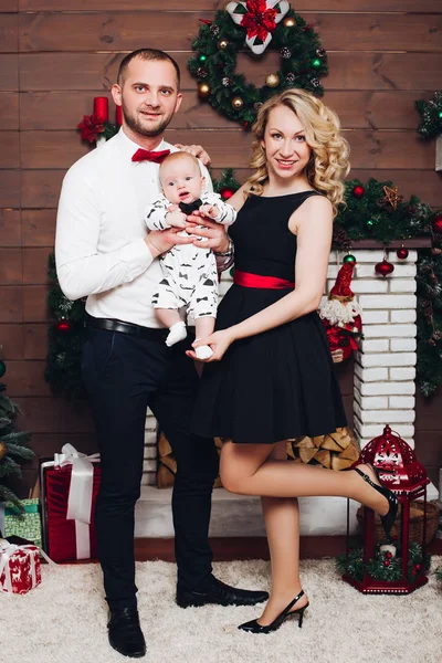 De familie staande elegantie samen in de buurt van open haard, zoon knuffelen en zoenen. — Stockfoto