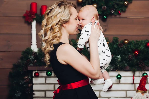 Menino com bela mãe loira abraçando no estúdio decorado para o Natal . — Fotografia de Stock