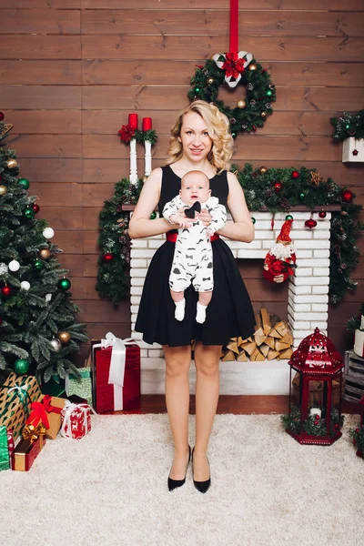 Niño con hermosa mamá rubia abrazando en estudio decorado para Navidad . —  Fotos de Stock