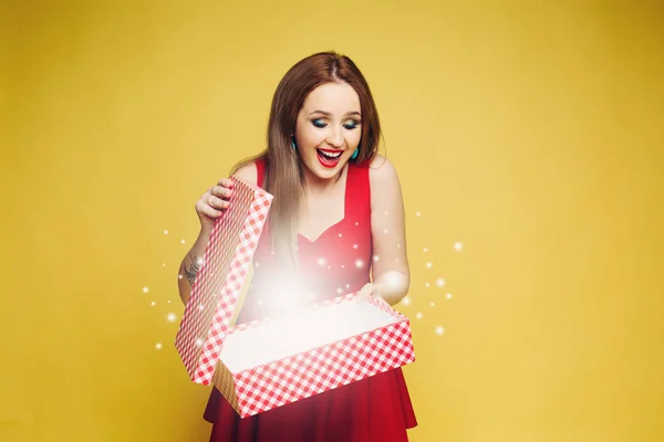 Glückliches brünettes Mädchen in schönem roten Kleid mit verpackten Weihnachtsgeschenken. — Stockfoto
