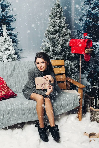 Atractiva mujer en vestido de punto con regalo de Navidad en el banco c —  Fotos de Stock