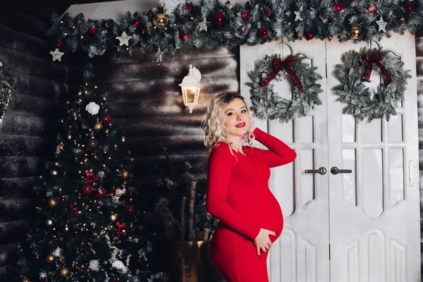 Szép terhes anya karácsonyi piros jelentő berendezett stúdió. — Stock Fotó