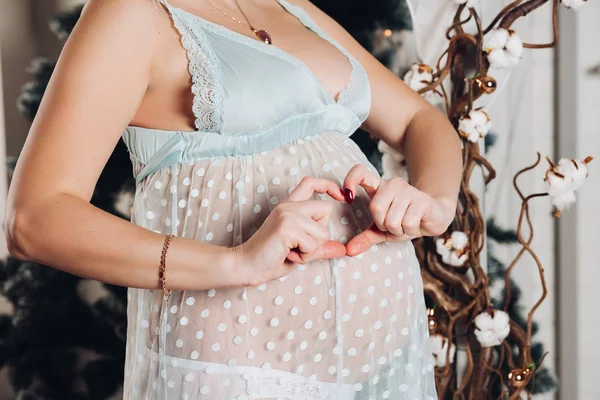 Onherkenbaar zwangere vrouw met handen in hart vorm aan de buik. — Stockfoto