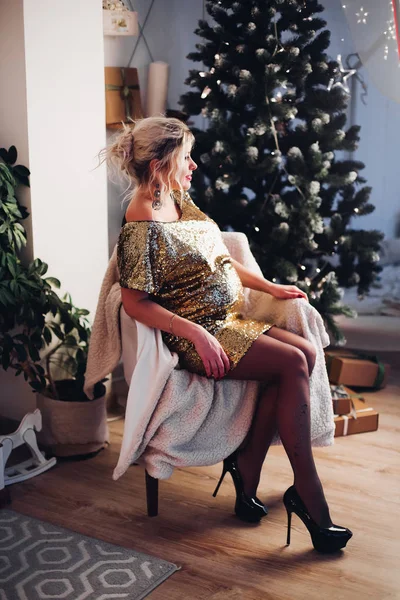 Donna incinta elegante in poltrona contro l'albero di Natale . — Foto Stock