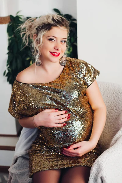 Gelukkig zwangere vrouw in mooie partij jurk omarmen haar buik. — Stockfoto