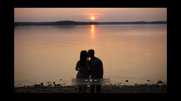 Silueta de pareja romántica caminando a orillas del lago y besándose al atardecer . — Foto de Stock
