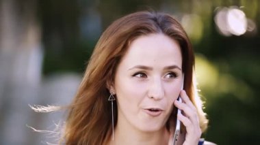 Gülümseyen güzel kadın cep telefonu açık havada yolu ile konuşmak.