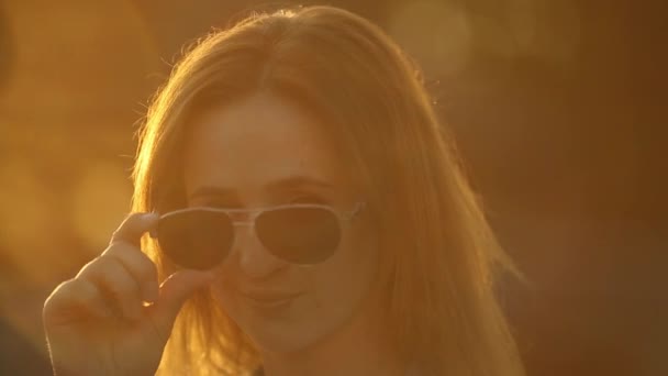 Mujer atractiva teniendo una conversación a través del teléfono móvil en la luz del sol brillante . — Vídeos de Stock