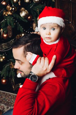 Lovely baby on dads shoulder at Christmas. clipart