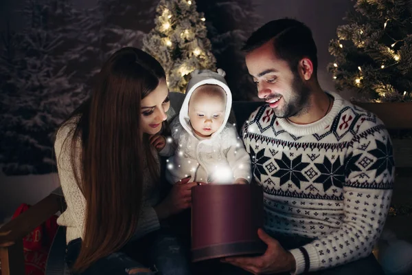 Milující šťastné rodiče s dítětem hledá uvnitř vánoční dárek — Stock fotografie