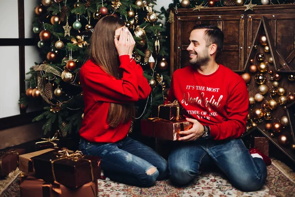 Happy man covering his girlfriends eyes at Christmas. — Stock Photo, Image