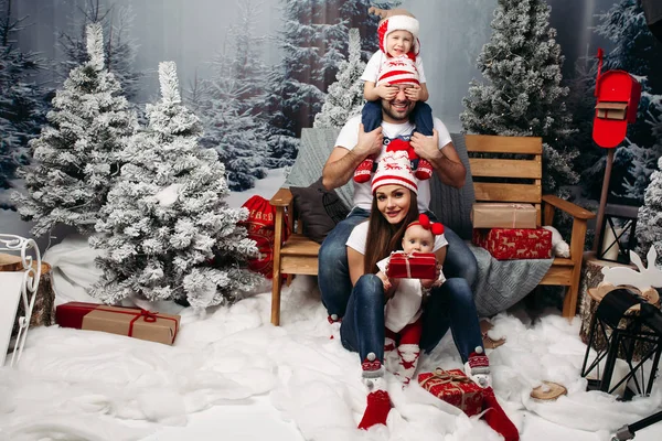 Familie samen met Kerstmis in kunstmatige bos onder sneeuwval — Stockfoto
