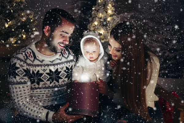 Milující šťastné rodiče s dítětem hledá uvnitř vánoční dárek — Stock fotografie