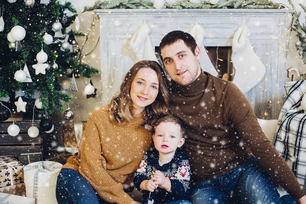 Familia sentados juntos en un sofá en un estudio decorado cerca del árbol de Navidad . —  Fotos de Stock