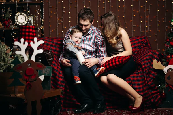 스튜디오에서 크리스마스 시간 동안 함께 소파에 앉아 작은 아이 함께 행복 한 가족 — 스톡 사진