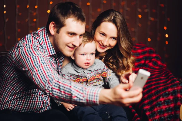 Keluarga positif dengan anak kecil berambut pirang mengambil foto di studio selama Natal . — Stok Foto