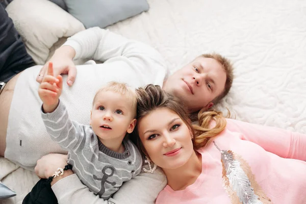 Retrato desde arriba de atractiva esposa y esposo con hijo acostado en la cama —  Fotos de Stock