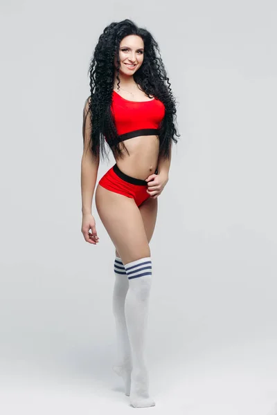 Atraktivní dívka v červené sportovní oděvy a bílé legíny představují. — Stock fotografie