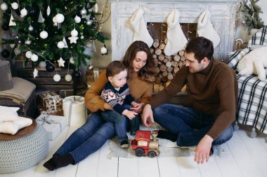 Birlikte Noel ağacı yakınındaki bir şekilde dekore edilmiş Studio kanepede oturan aile.